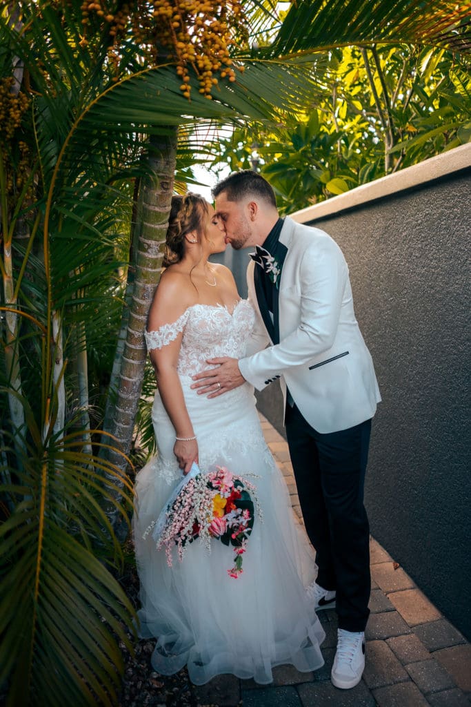 Bride and Groom kissing against palm tree at wedding in St. Pete